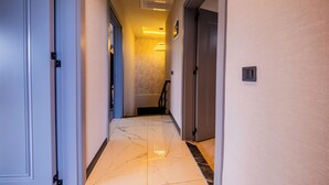 A hotel hallway with a marble floor, doors on both sides, and a light fixture on the ceiling.