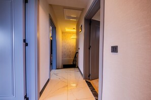 A hotel hallway with a marble floor, doors on both sides, and a light fixture on the ceiling.