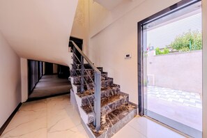 Eine moderne Treppe mit Marmorstufen und Metallgeländern, die zu einer Glastür führt.