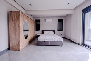 A modern bedroom with a large bed, a wooden wardrobe, and a large window. - Spacious 4-bedroom Detached luxury villa in peaceful Antalya Kemer Tekirova (ANTALYA)
