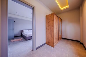 Une chambre moderne avec un lit, une armoire en bois et un couloir menant à une autre pièce.