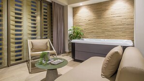 Una habitación moderna con sofá, camilla de masaje, separador de vidrio y planta en maceta.