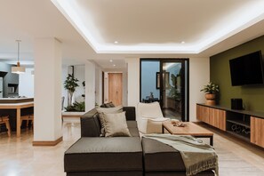 Una sala de estar moderna con un sofá, una mesa de centro y un televisor montado en la pared.