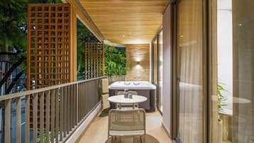 Un balcón con mesa y sillas, un jacuzzi y techo de madera.