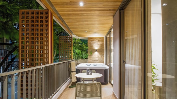 Un balcón con mesa y sillas, un jacuzzi y techo de madera.