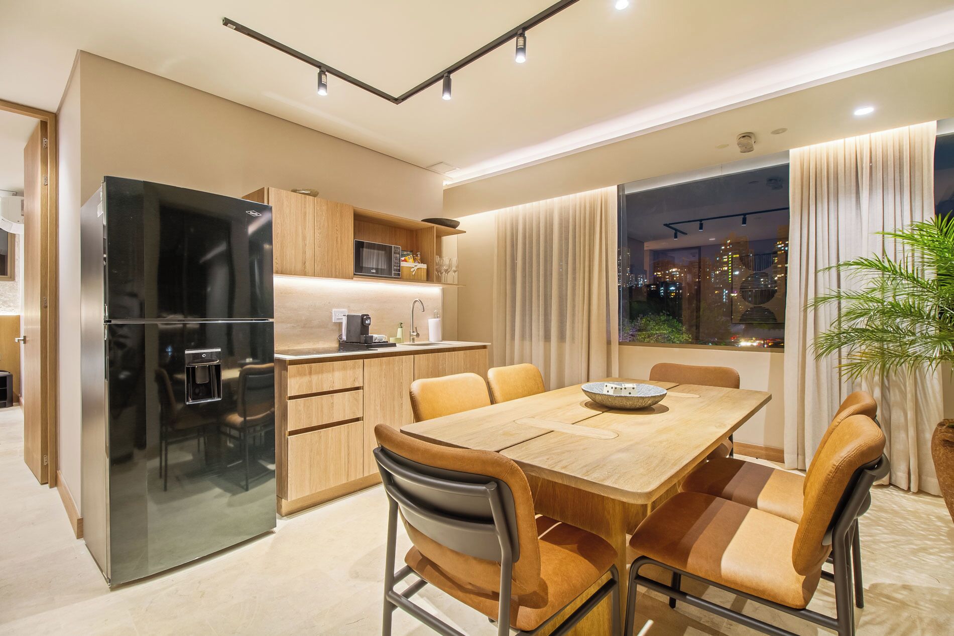 Una cocina moderna con refrigerador integrado, armarios de madera y un comedor con mesa y sillas.