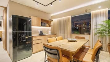 Una cocina moderna con refrigerador integrado, armarios de madera y un comedor con mesa y sillas.