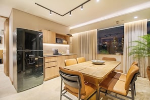 A modern kitchen with a built-in refrigerator, wooden cabinets, and a dining area with a table and chairs.
