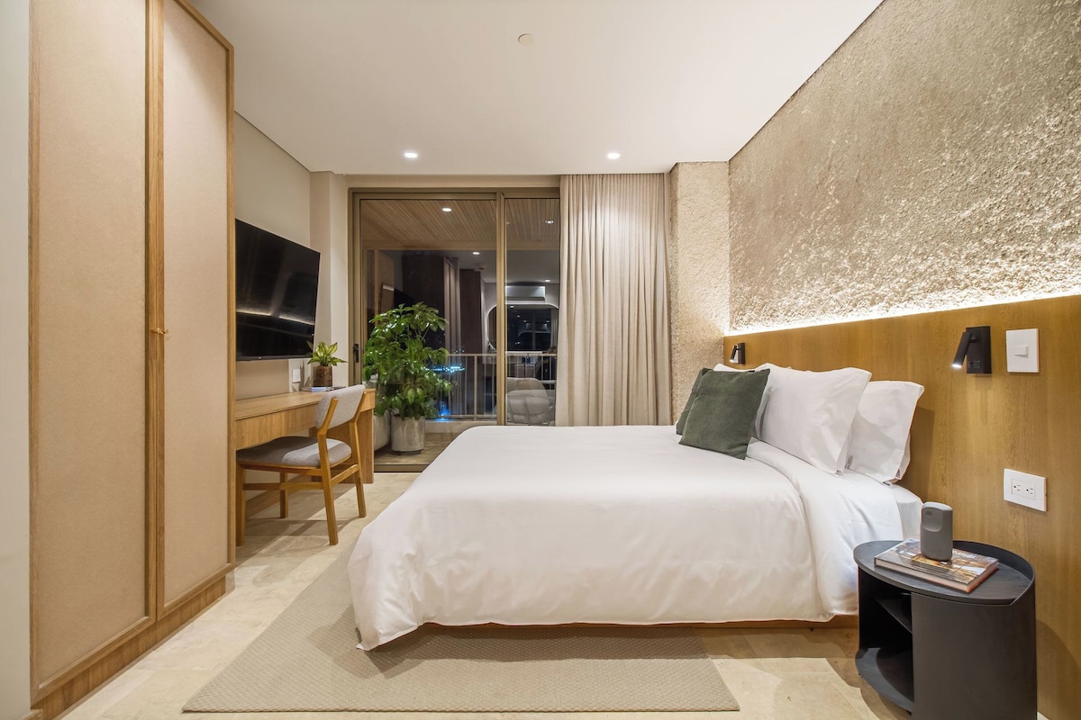 A modern bedroom with a bed, bedside table, and a desk with a chair.