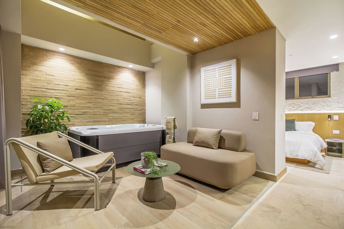 A modern room with a sofa, a small table with a plant, a hot tub, and a window with a view.