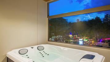 Un baño moderno con bañera, ventana con vista a la ciudad y techo de madera.