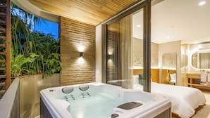 Un dormitorio moderno con una bañera grande, una cama y un baño con espejo.