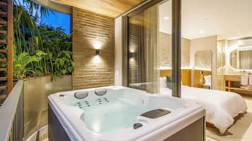 Un dormitorio moderno con una bañera grande, una cama y un baño con espejo.
