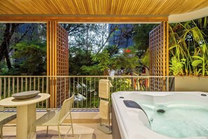 Un balcón con jacuzzi, una mesa y sillas.