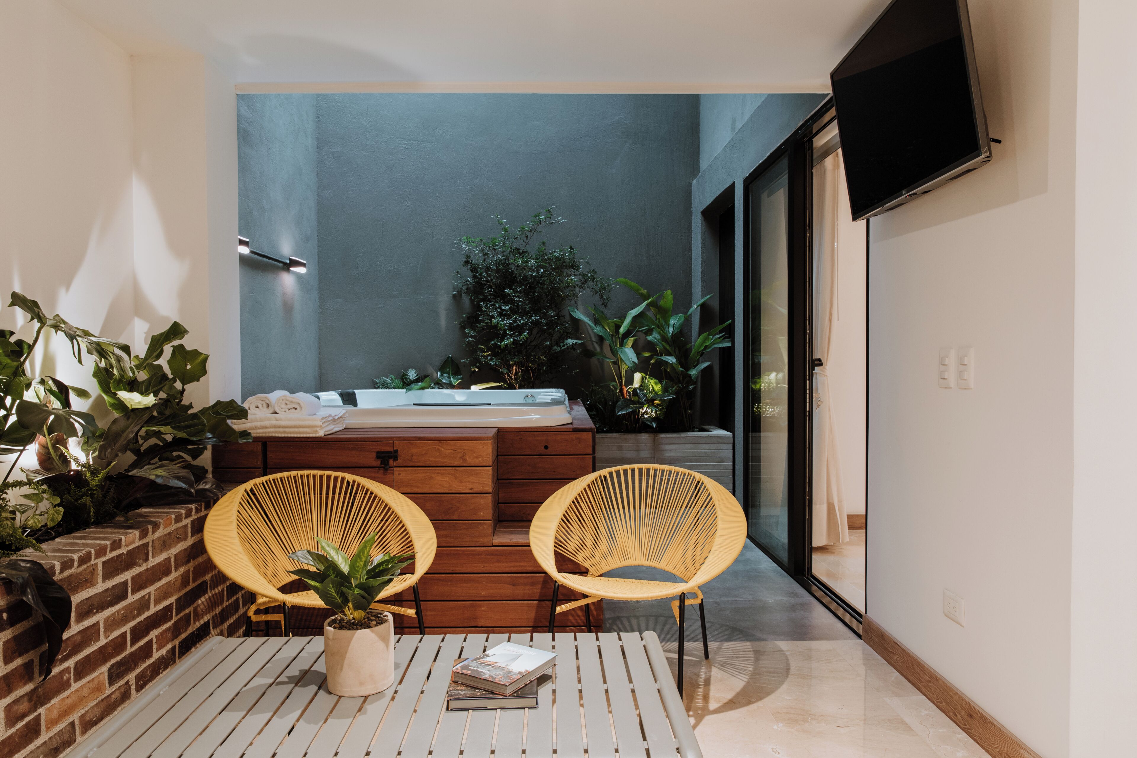Un baño moderno con una bañera, dos sillones de mimbre y diversas plantas.