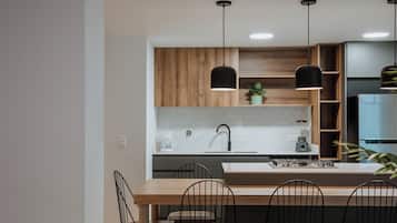 Una cocina moderna con una isla central, lámparas colgantes negras y una estufa integrada.