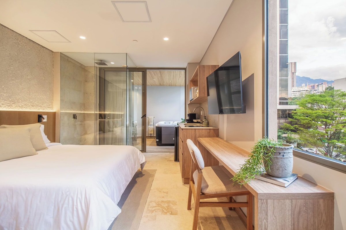 A modern hotel room with a bed, desk, and TV.
