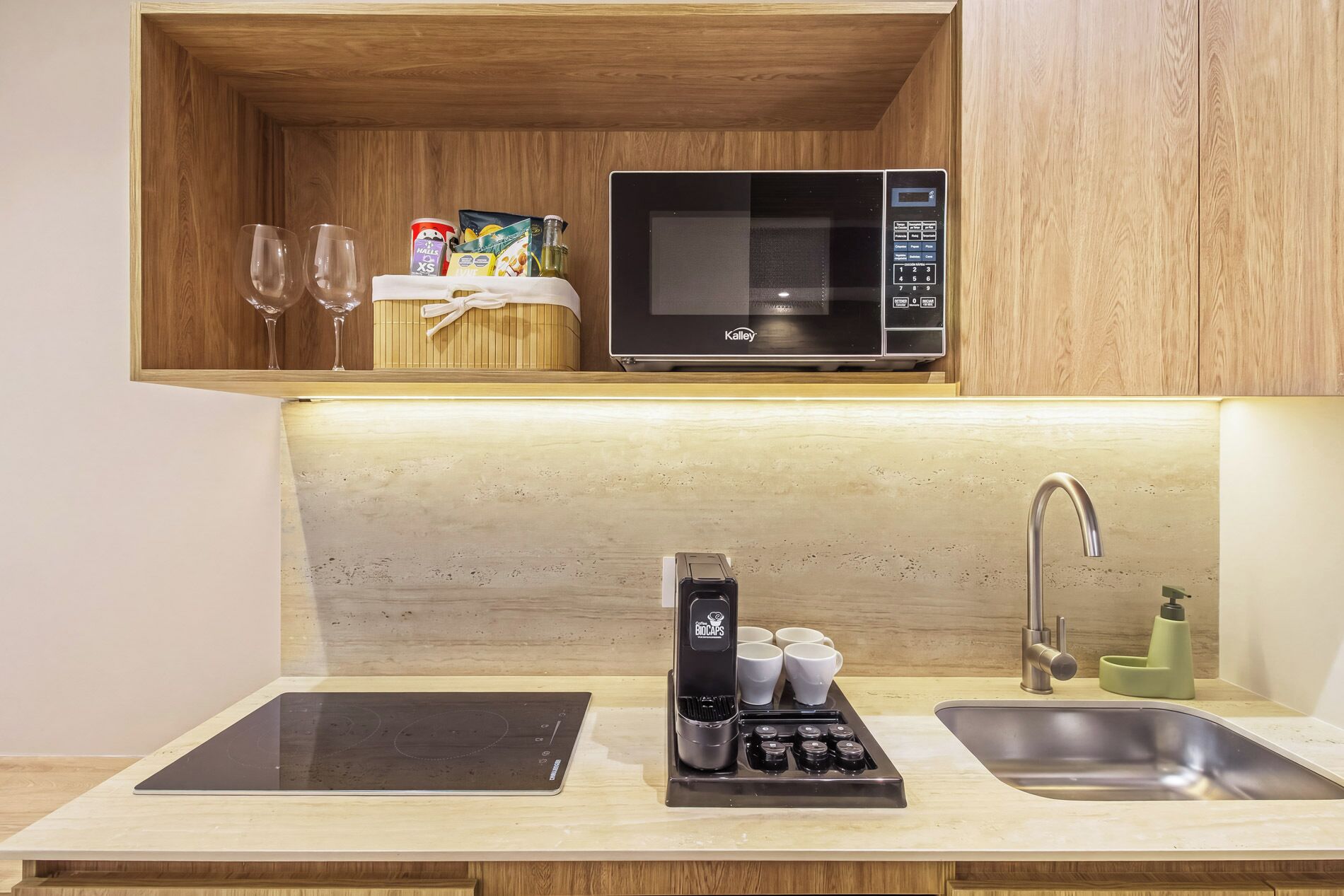 Una kitchenette con microondas, cafetera y lavamanos.