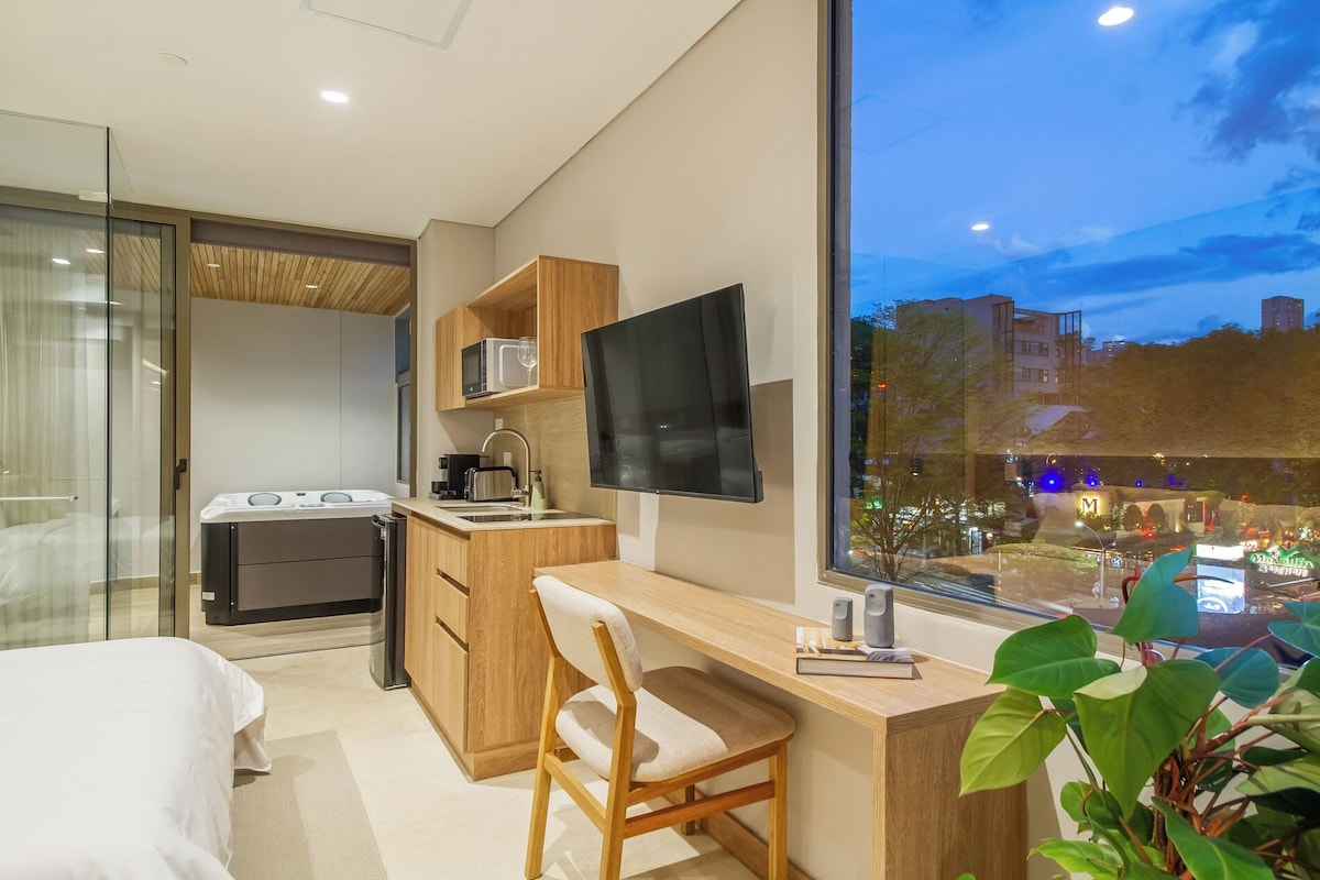 A modern hotel room with a bed, a desk, a chair, a television, and a large window.