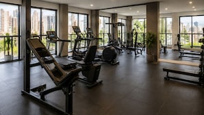 Ein Fitnessstudio mit Trainingsgeräten, großen Fenstern und Blick auf die Stadt.
