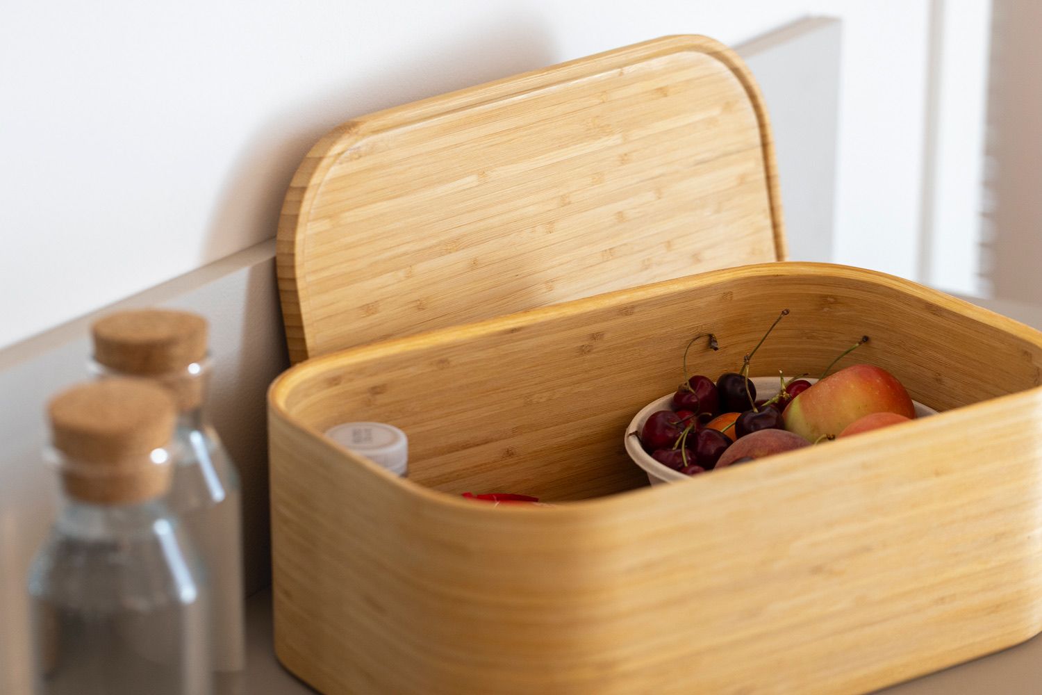 Eine Holzkiste mit Deckel, gefüllt mit Obst und einer kleinen Flasche.
