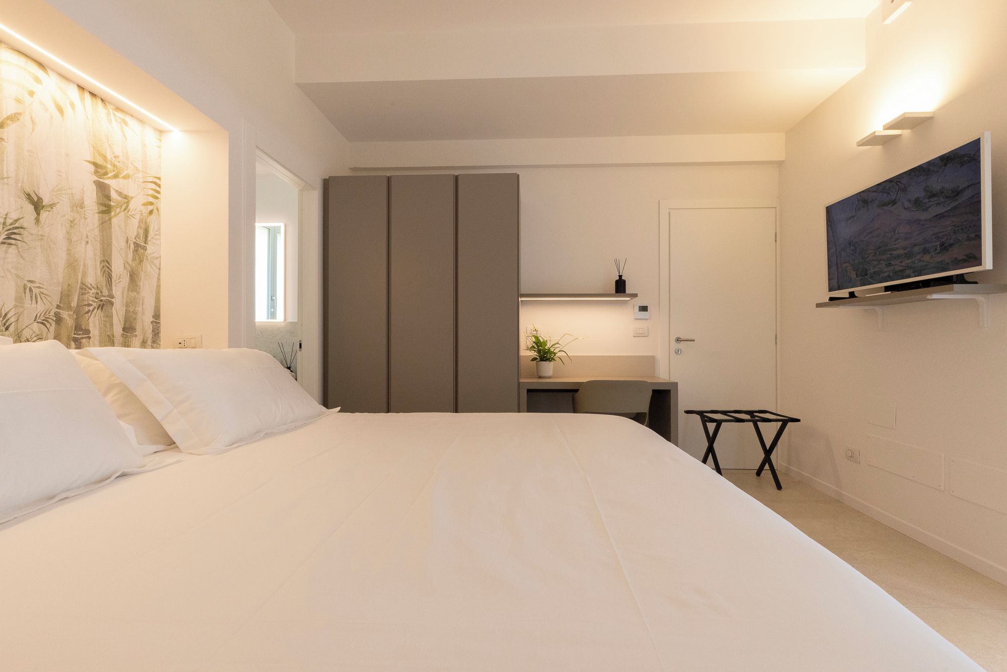 Ein Schlafzimmer mit Bett, Schreibtisch, Stuhl, Fernseher und Kleiderschrank.