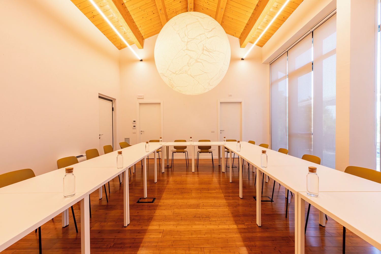 A conference room with a long table, chairs, and a large circular light fixture on the ceiling.