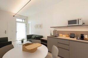 Una cucina moderna con forno a microonde, lavandino e macchina del caffè. C'è un'area pranzo con un tavolo rotondo e sedie.