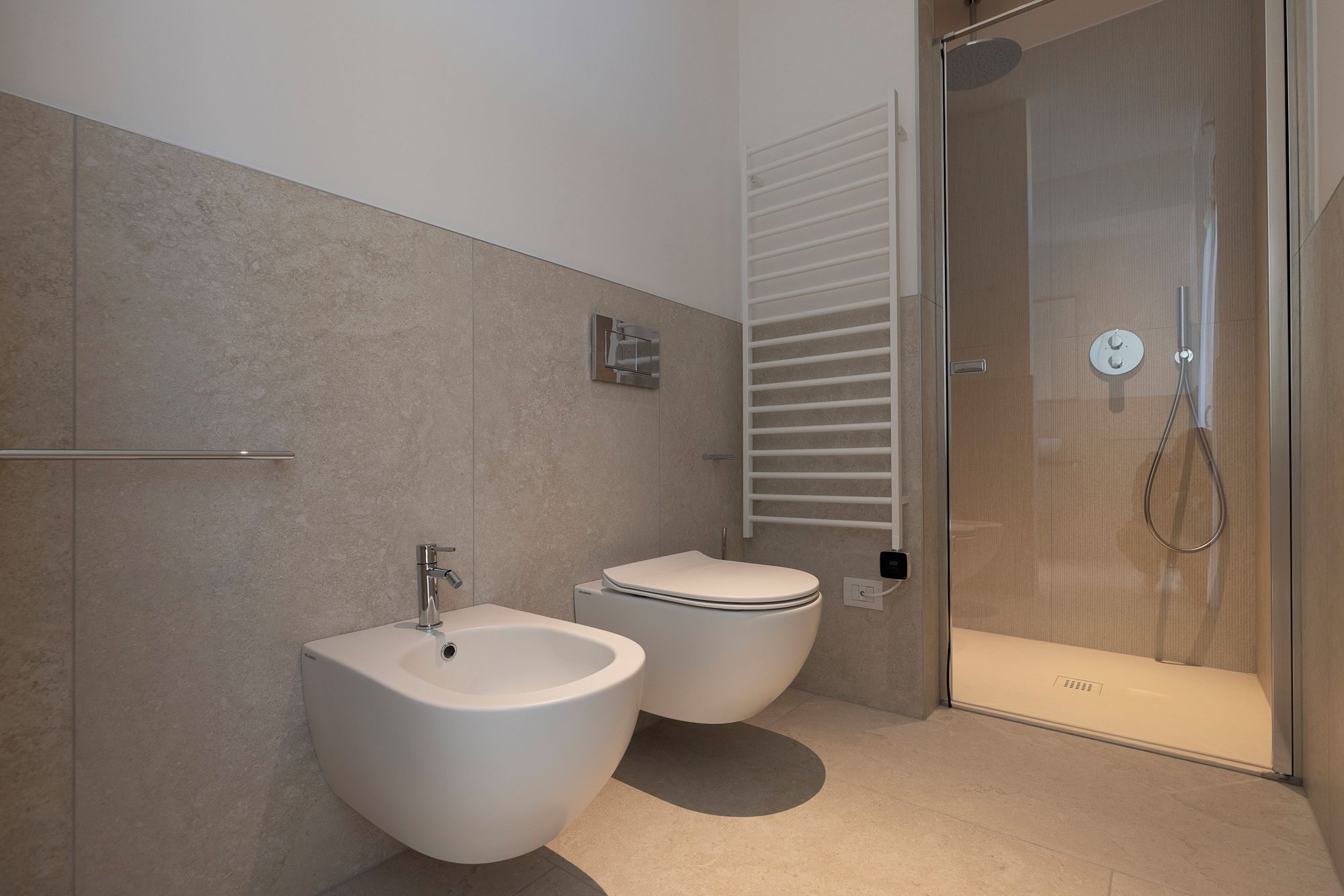 Un bagno moderno con bidet, WC e cabina doccia in vetro.
