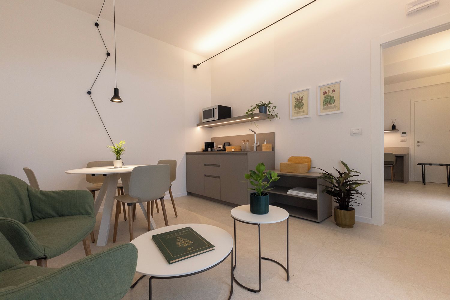 Ein modernes Wohnzimmer mit Essbereich, einer Couch, einem kleinen runden Tisch und einer Küchenzeile.