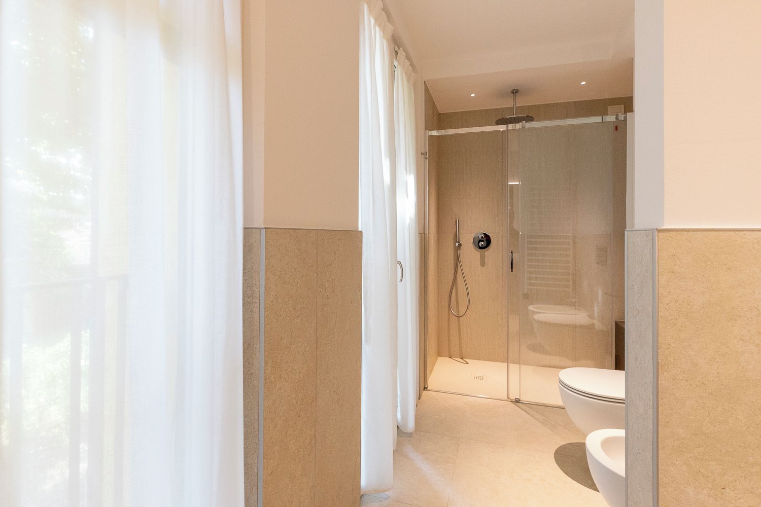 A modern bathroom with a glass-enclosed shower, a toilet, and a showerhead.