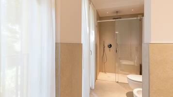 A modern bathroom with a glass-enclosed shower, a toilet, and a showerhead.