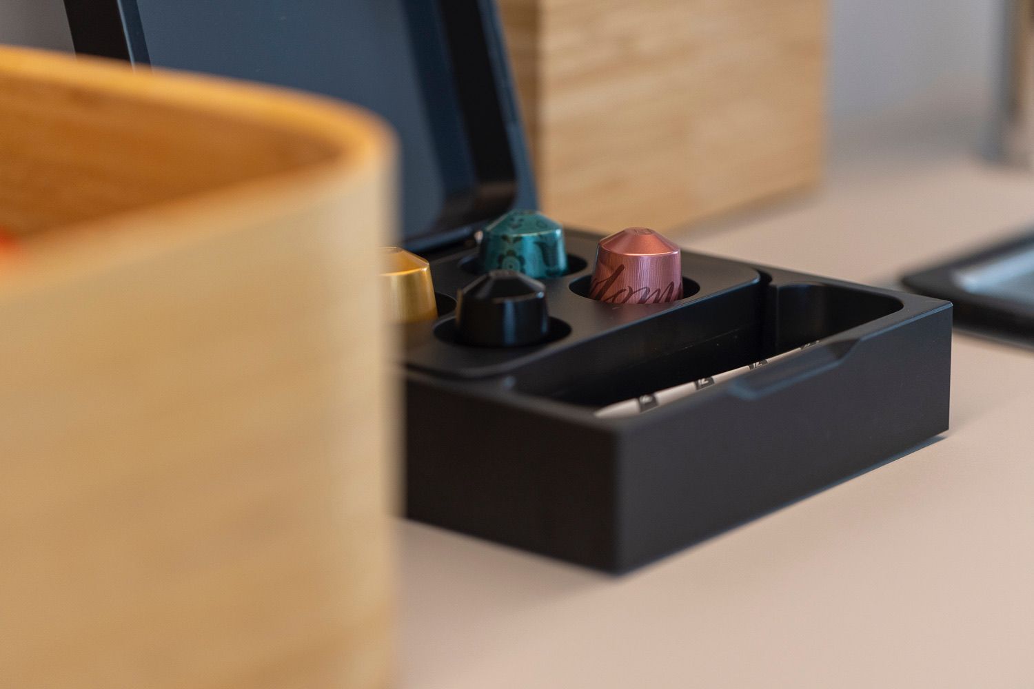 A black tray with three metallic objects, possibly a set of keys or tools, on a wooden surface.