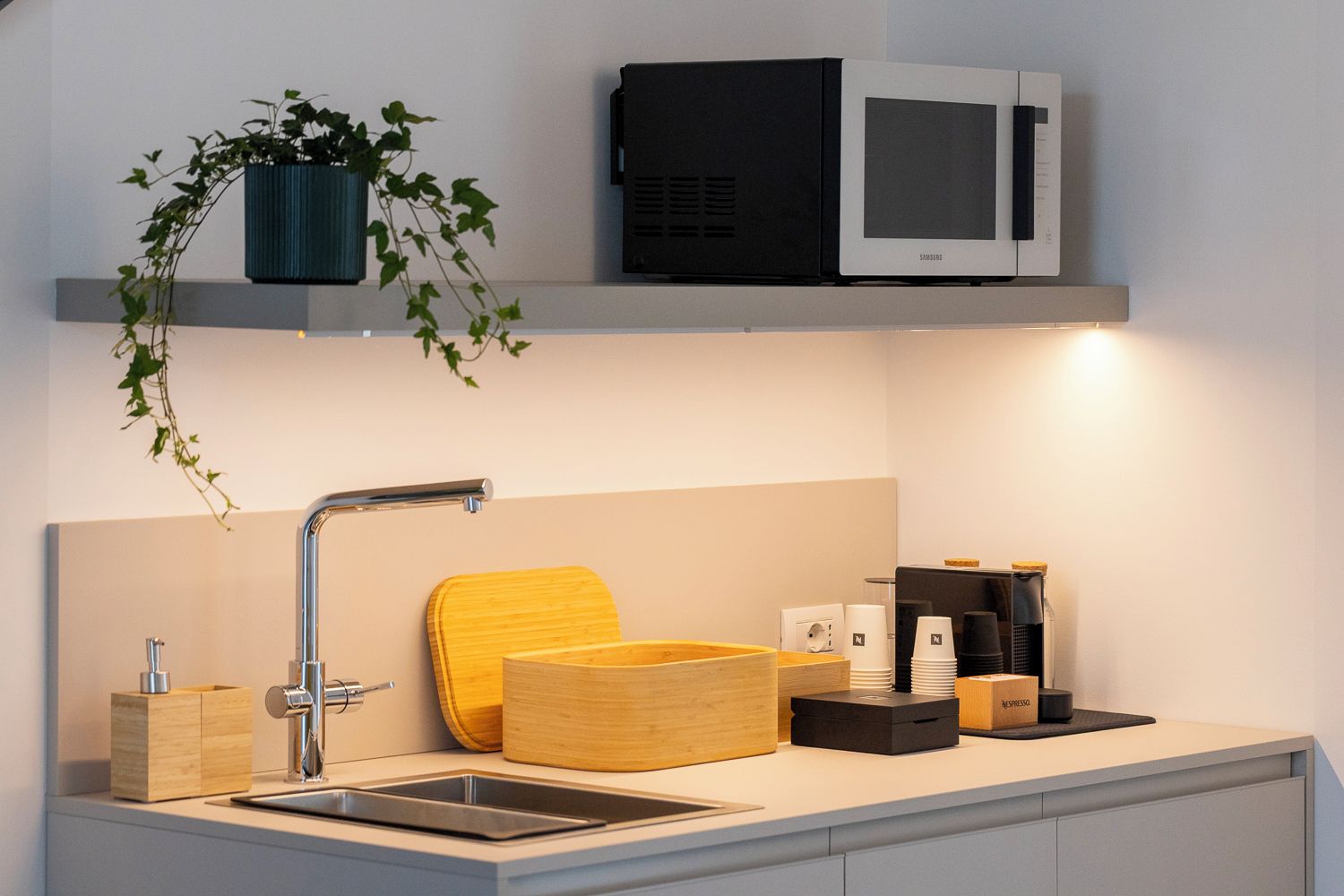 Una cocina moderna con un lavamanos de acero inoxidable, un microondas y una cafetera.