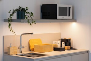 Una cocina moderna con un lavamanos de acero inoxidable, un microondas y una cafetera.