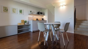 A modern kitchen with a dining area, wooden flooring, and a staircase. - Grow Green (Caponago)