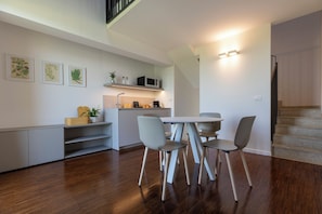 Una cocina moderna con comedor, suelo de madera y una escalera.