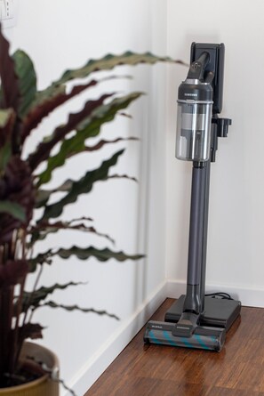 A Samsung vacuum cleaner on a wooden floor next to a white wall.