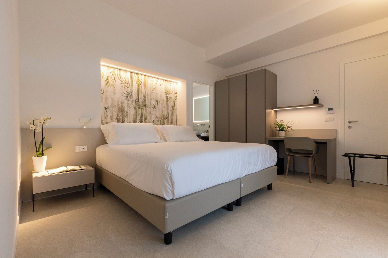 Un dormitorio moderno con cama, mesitas de noche, escritorio y una silla.