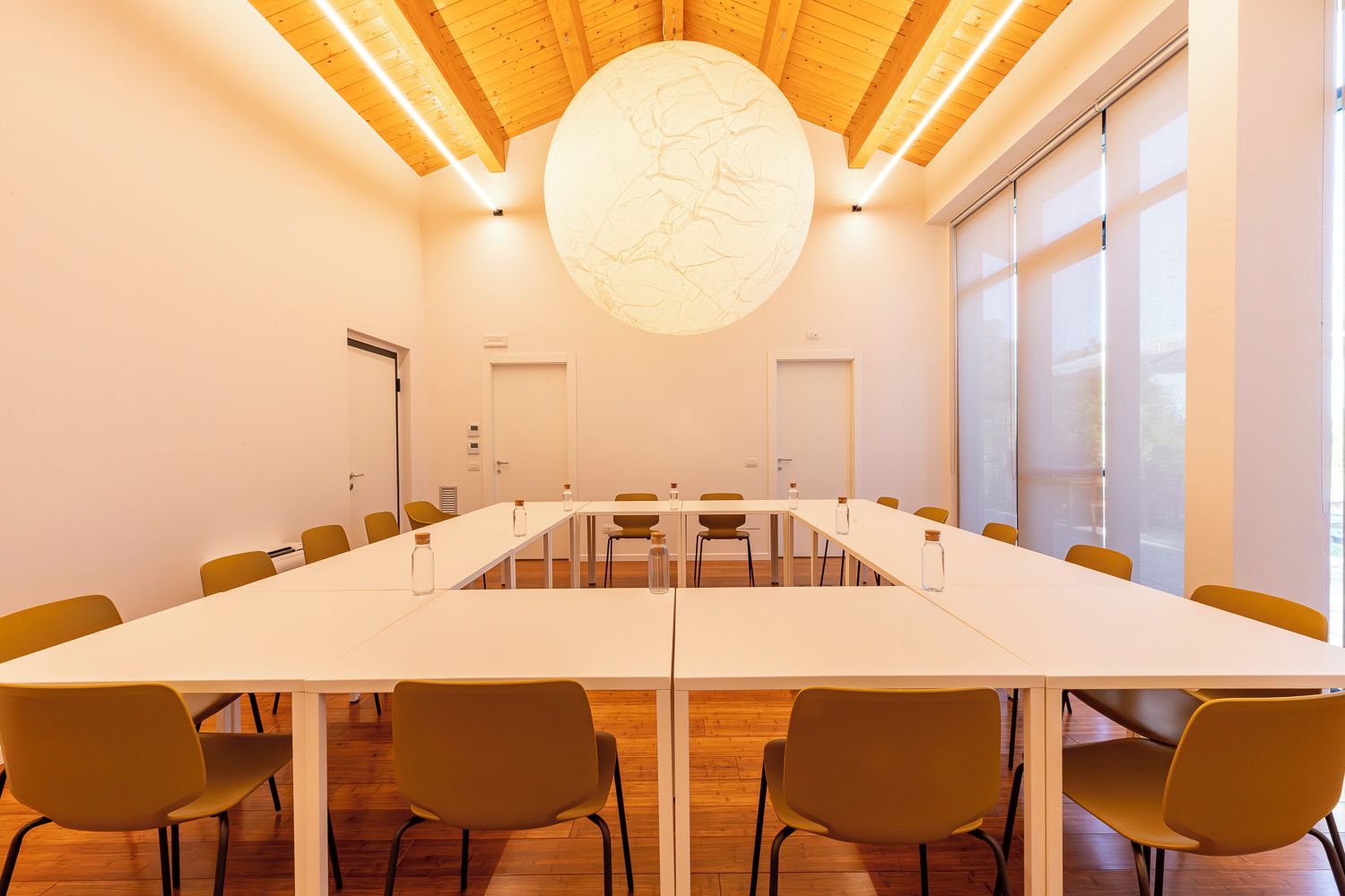 A conference room with a long table, chairs, and a large circular light fixture on the ceiling.