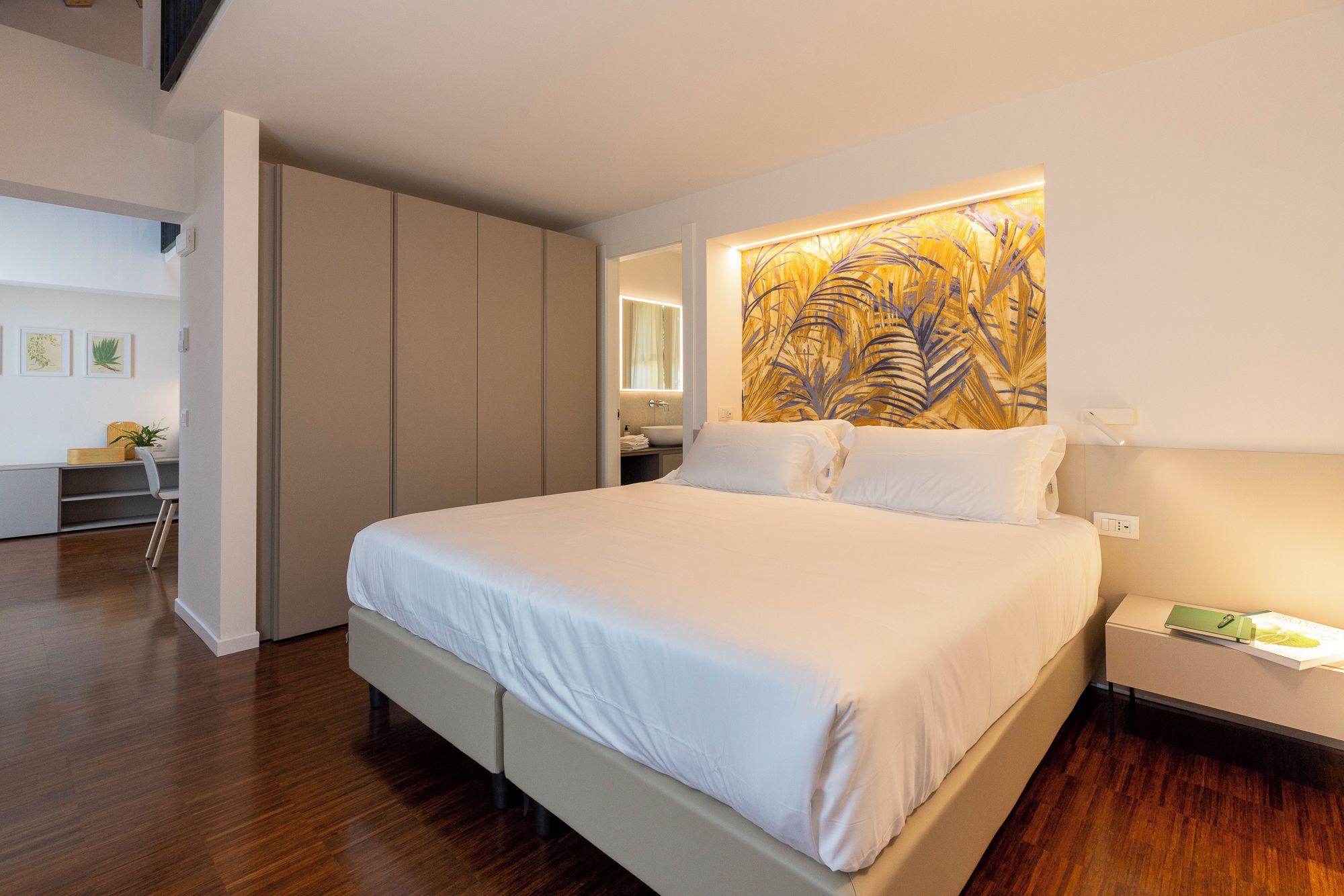 Un dormitorio moderno con una cama grande, un armario empotrado y una obra de arte en la pared.