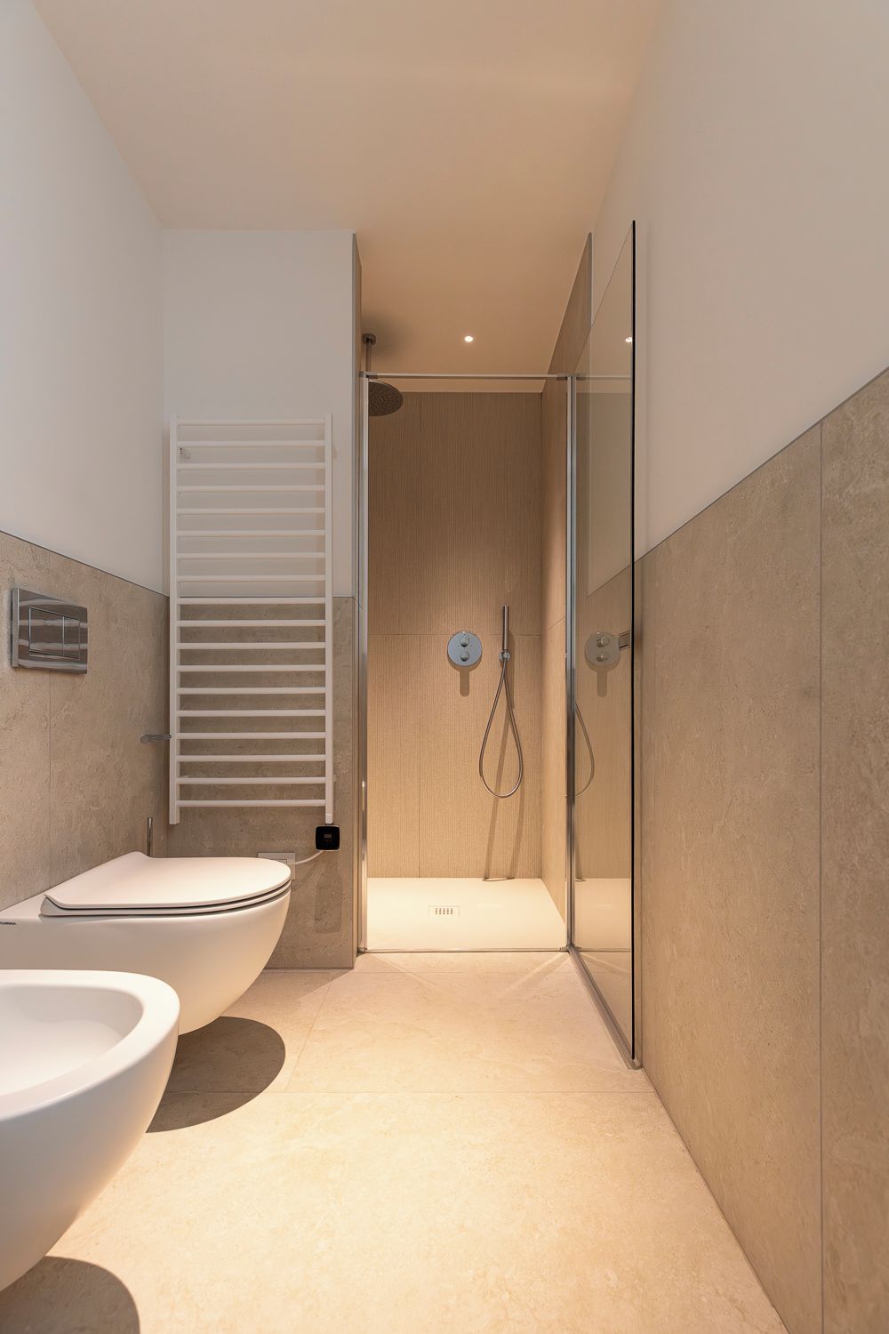 Un baño moderno con ducha de vidrio, inodoro blanco y bidé.