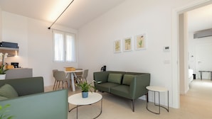 A modern living room with a sofa, chairs, a coffee table, and a dining area with a table and chairs. - Grow Green (Caponago)