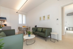 Una sala moderna con sofá, sillas, una mesa de centro y un comedor con mesa y sillas.