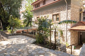 A stone building with a courtyard, surrounded by trees and potted plants. - Beach Suite İcmeler (Ula Mimarisi) (Muğla)