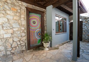 A stone building with a colorful door and a potted plant. - Beach Suite İcmeler (Ula Mimarisi) (Muğla)