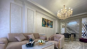 Uma sala de estar luxuosa com sofá, poltrona, mesa de centro e lustre.