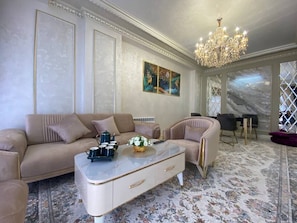 En elegant stue med sofa, lænestol, sofabord og en lysekrone.