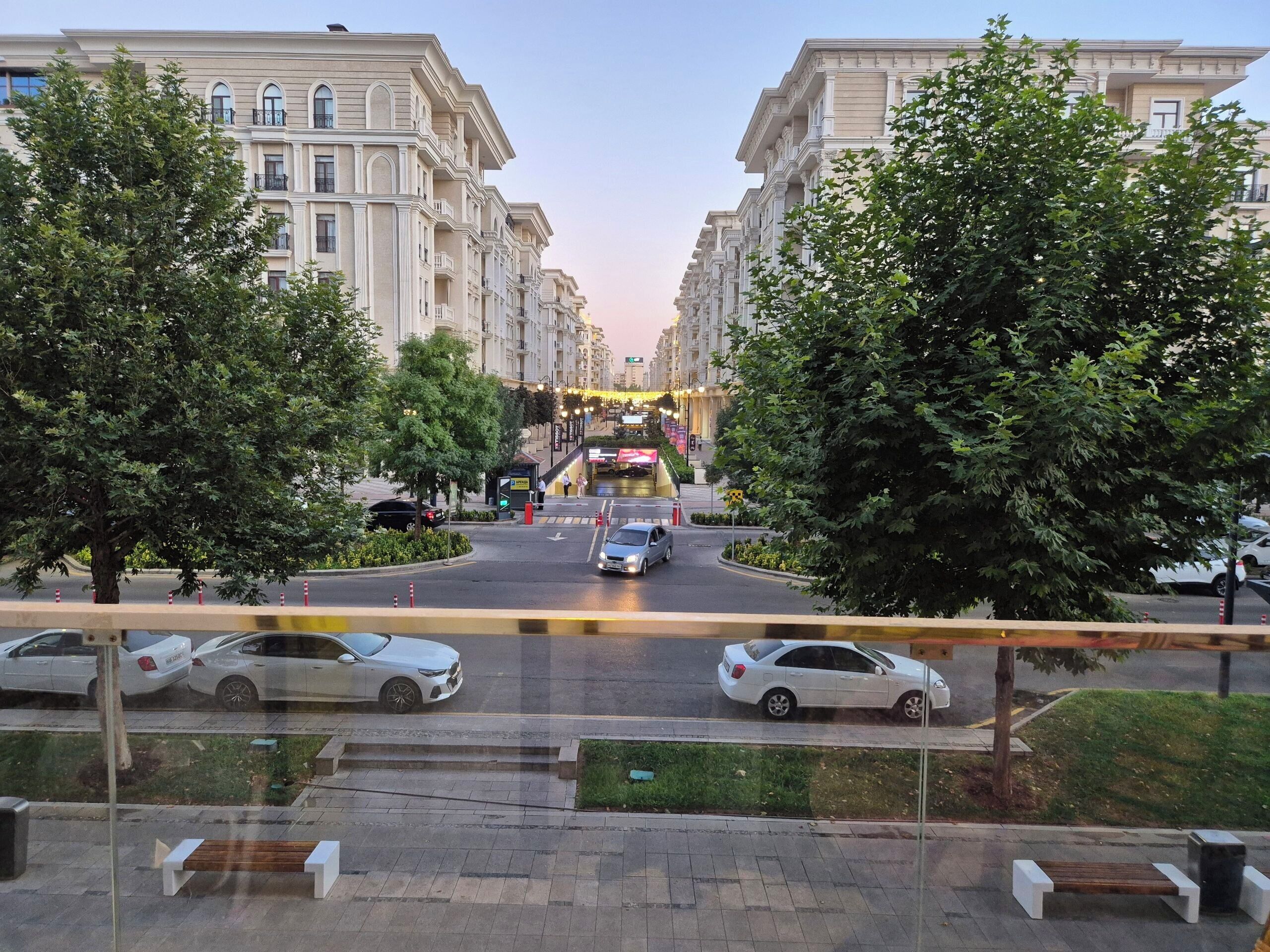 A street view with a row of buildings, a pedestrian crossing, and cars on the road.