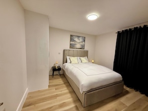 A bedroom with a bed, bedside tables, a ceiling light, and a painting on the wall. - Brand New Luxury 4 Bedroom 4 Bathroom Surbiton Flat | 
20min London Waterloo (Surbiton)